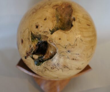 Buckeye burl sphere resting on a mesquite base